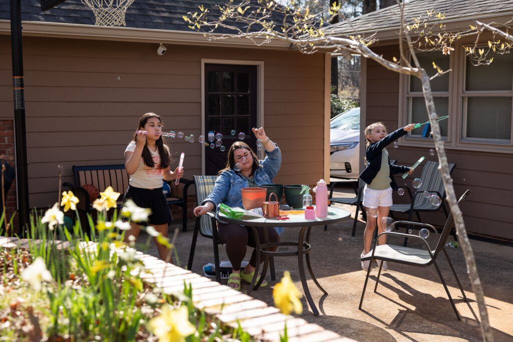 At-home easy spring family photos showing real life in Raleigh, blowing bubbles on the back patio
