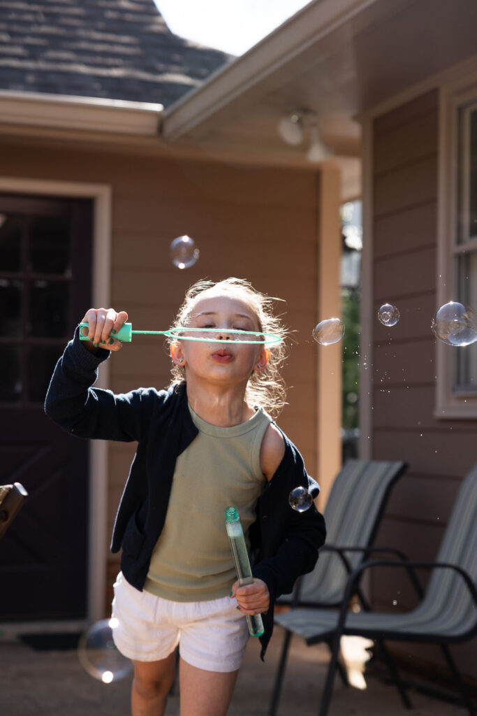 girl blowing bubbles during Springtime Candid Documentary Family Photos in Raleigh at home