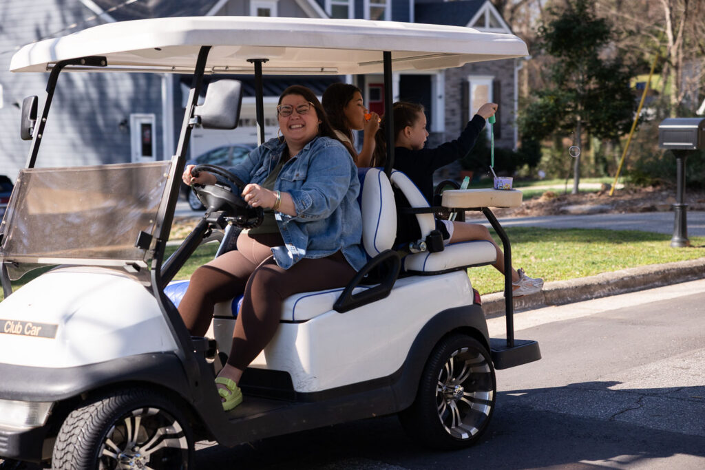 Liz Chavez cruising on a golf cart while capturing real life family fun with Springtime Candid Documentary Family Photos in Raleigh