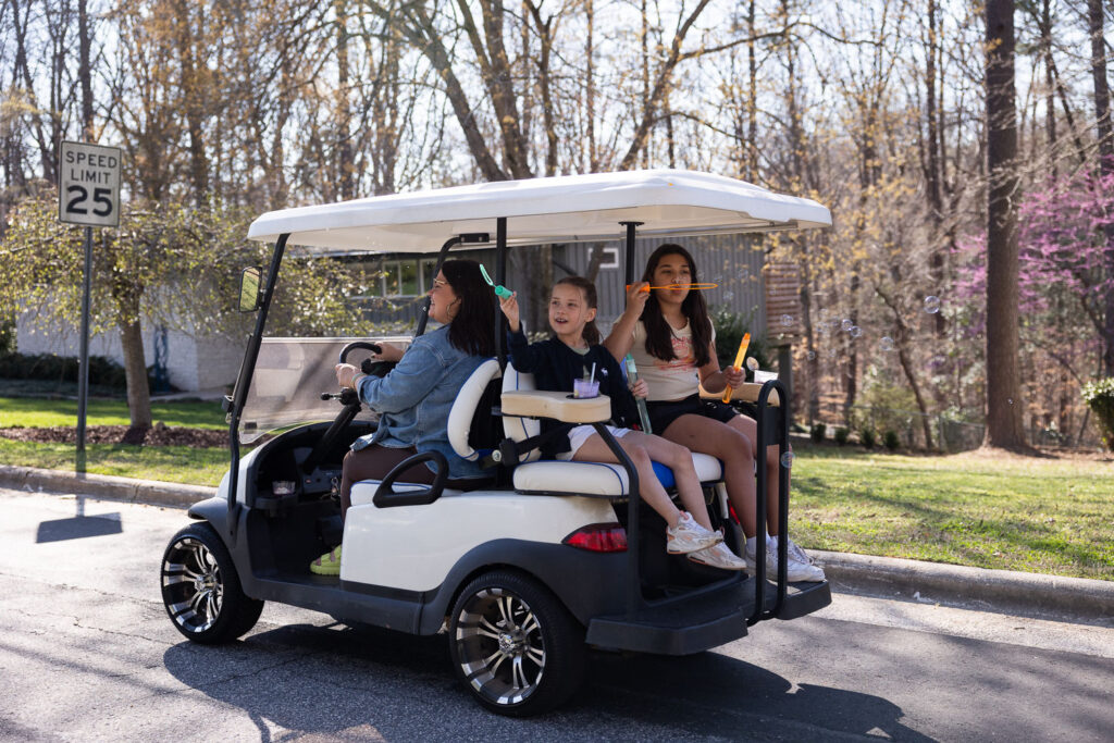 Cruising on a golf cart with bubbles while capturing your family's real life with Springtime Candid Documentary Family Photos in North Hills neighborhood Raleigh