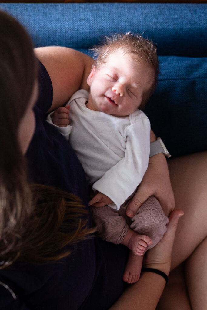 Natural newborn photography in Raleigh - aerial photo of newborn baby girl being held by her mom on the couch