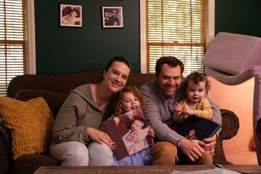 A mom and dad sit with their 3-year-old and 1-year-old with the kids' New Life Collection keepsake albums 