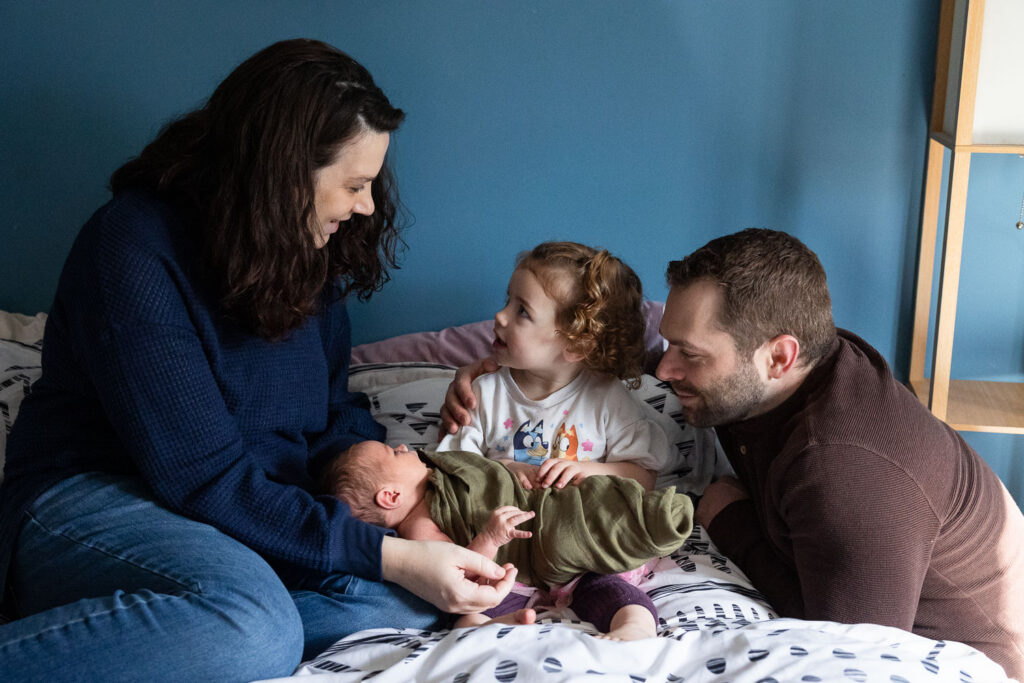 Raleigh in-home newborn photo session, family of four snuggled on bed