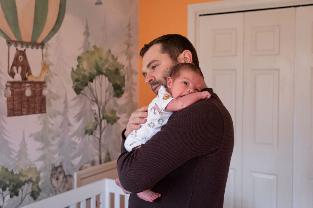 Dad holds newborn son in the nursery during Raleigh newborn session