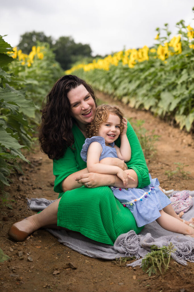 Mom and daughter photo session sitting on a blanket at Dix Park sunflower field