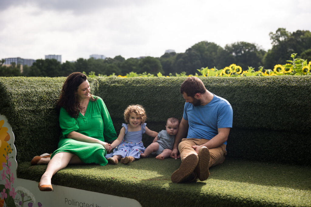 Big green grass couch photo op at Dorothea Dix Park sunflower field, family of four photo session