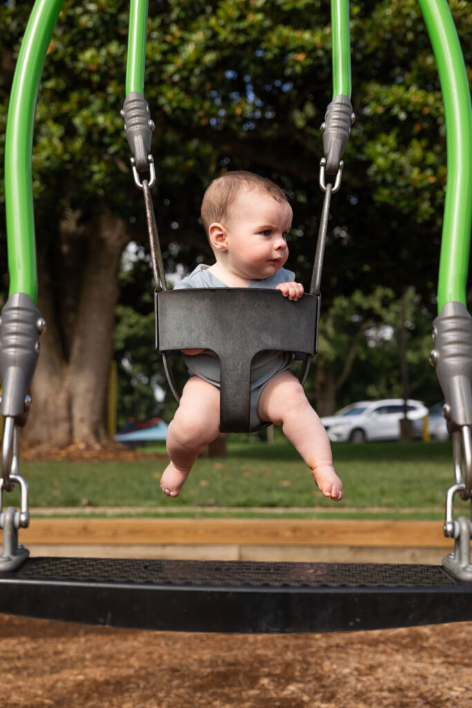 Baby photo on tandem swing at Dorothea Dix Park Magnolia Room area 
