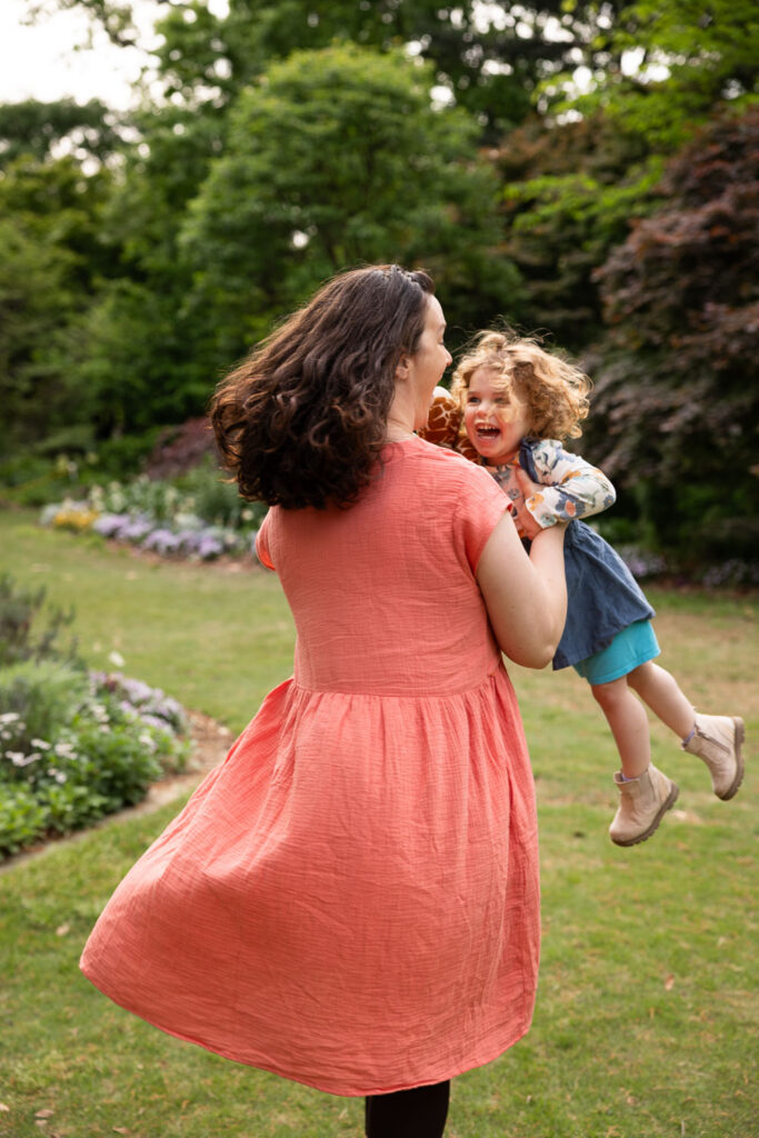 Mom spins toddler girl around in circles at Fred Fletcher Park