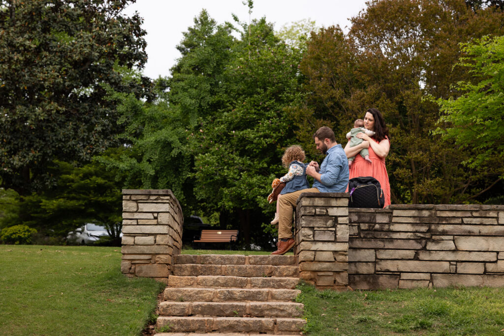 Candid family photo at Fred Fletcher Park showing dad adjusting daughter's dress and mom holding baby boy