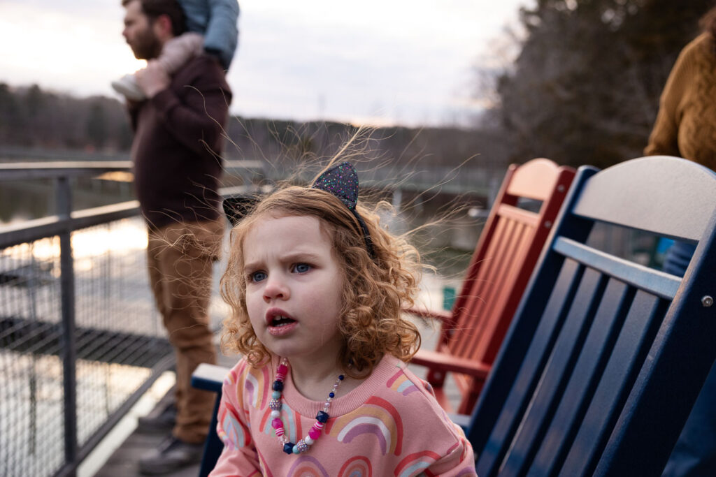 Static electricity hair as toddler girl sits in chair at Lake Johnson Raleigh family photo session