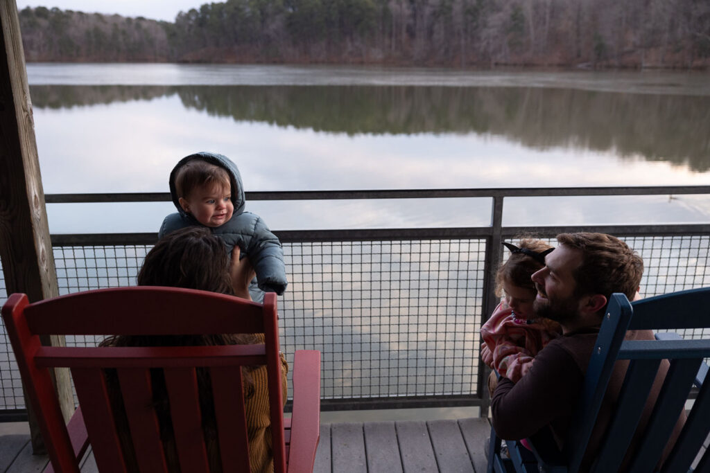 Lake Johnson Raleigh candid documentary family photo session, family sits in rocking chairs overlooking the lake