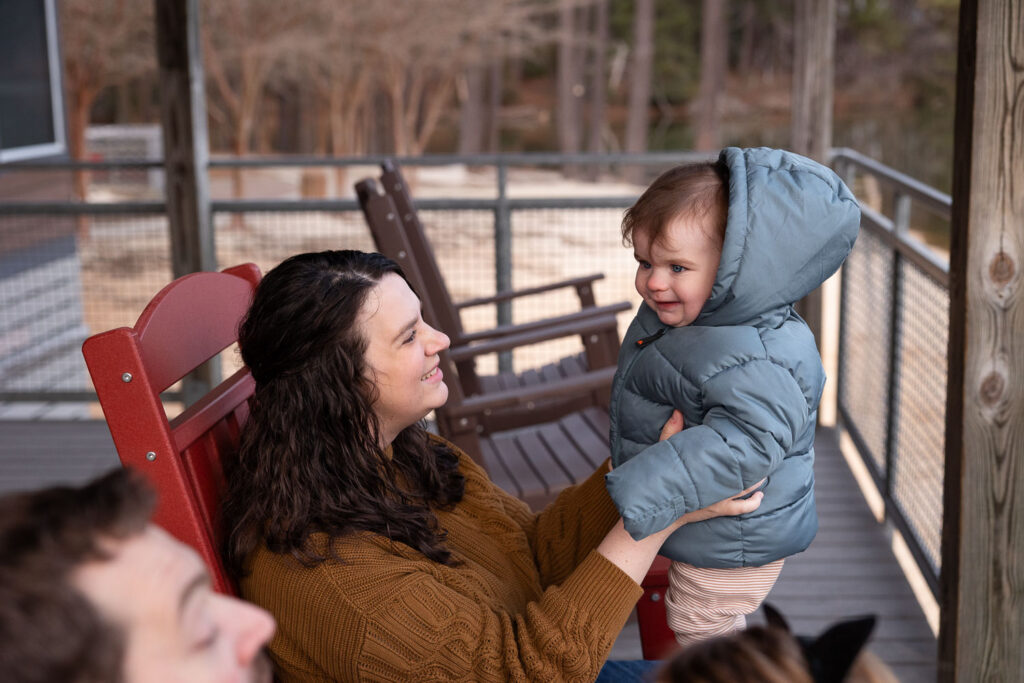 Mom holds 1-year-old son while sitting in rocking chair at Lake Johnson photo session