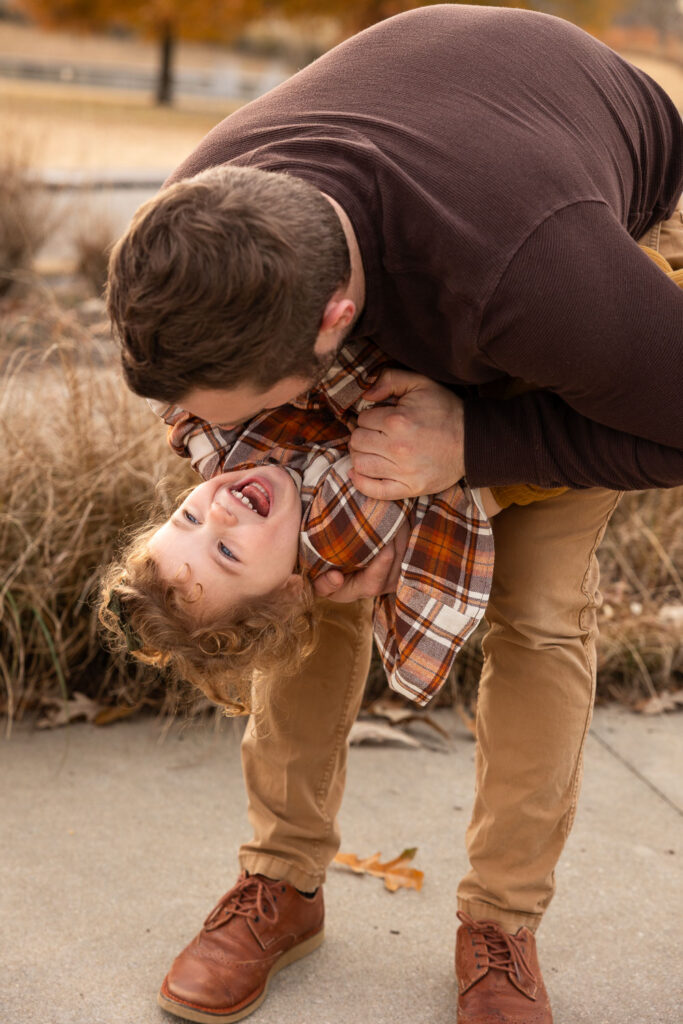 Raleigh family photo showing dad flipping toddler daughter upside-down while she laughs