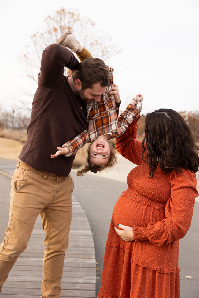 Raleigh maternity session at NCMA, dad holding toddler daughter upside-down