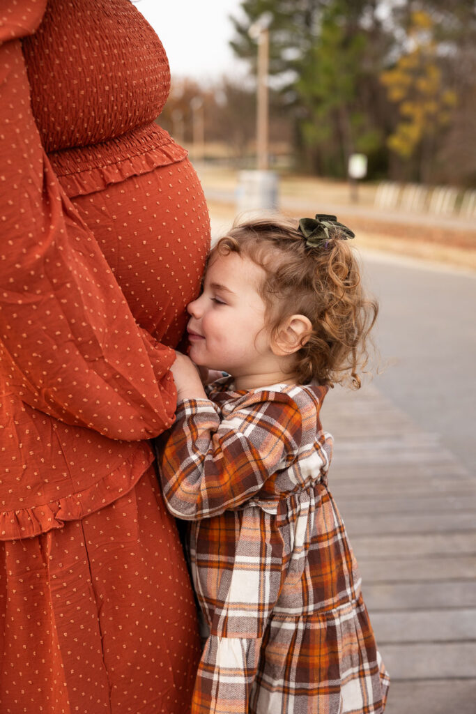 Toddler daughter kissing mom's baby belly during Raleigh maternity photos