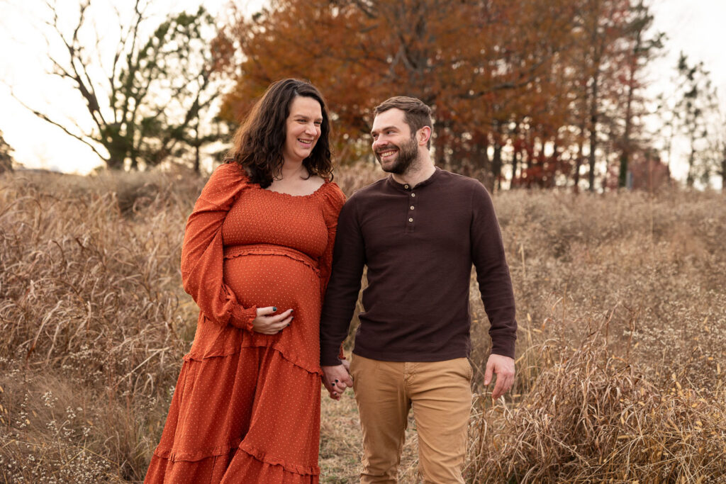 Raleigh maternity session at NCMA in the fall, mom and dad walking through tall grass