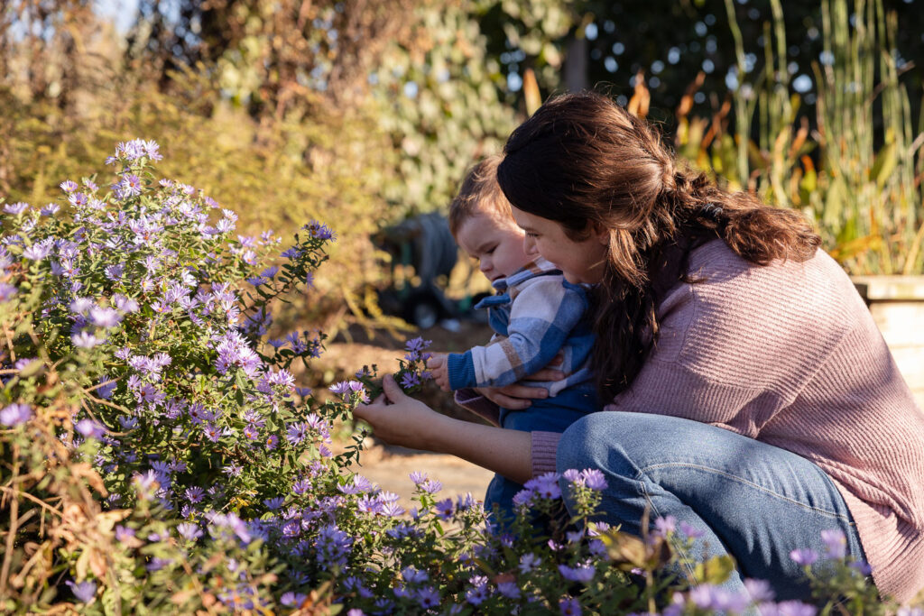 Mom and baby boy look at and touch flowers at Prairie Ridge Ecostation
