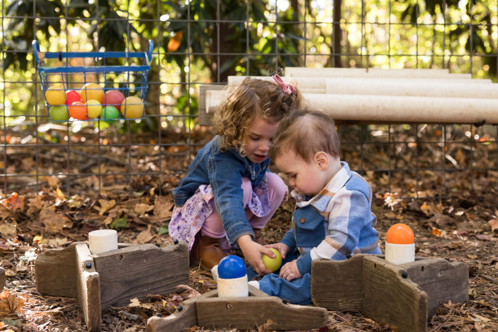 Candid family photos at Prairie Ridge Ecostation Raleigh, toddler hands her baby brother a ball to play with