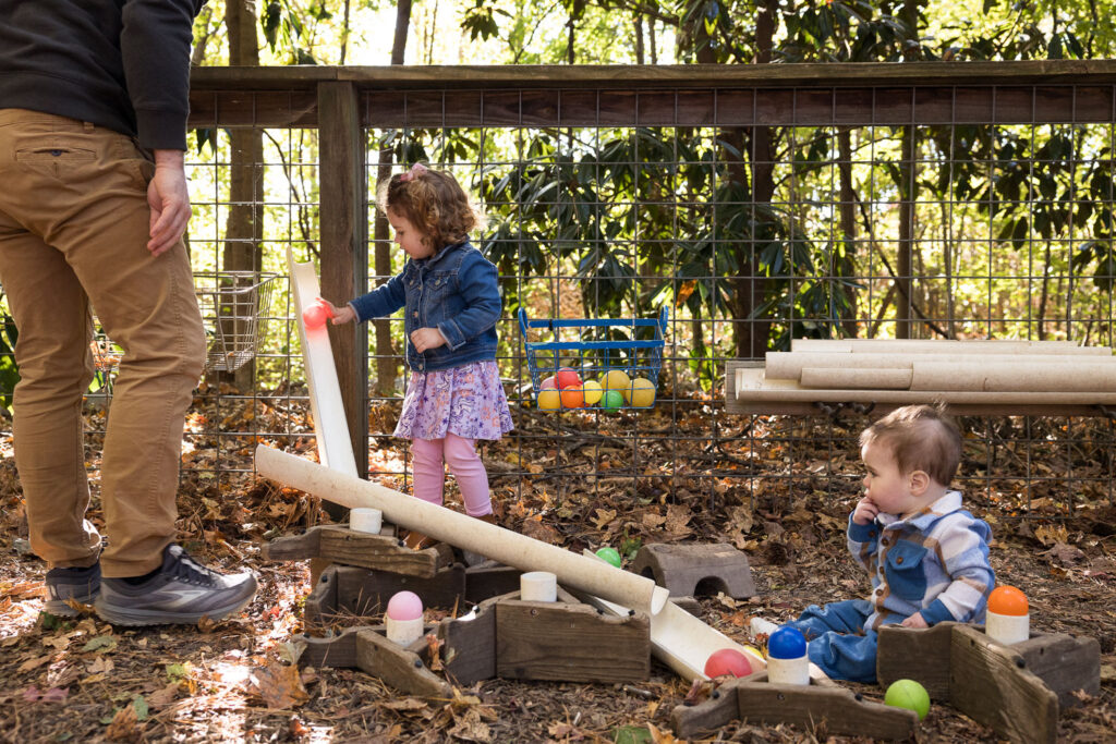 Candid documentary family photos at Prairie Ridge Ecostation Raleigh, toddler and baby brother play with balls and ramps