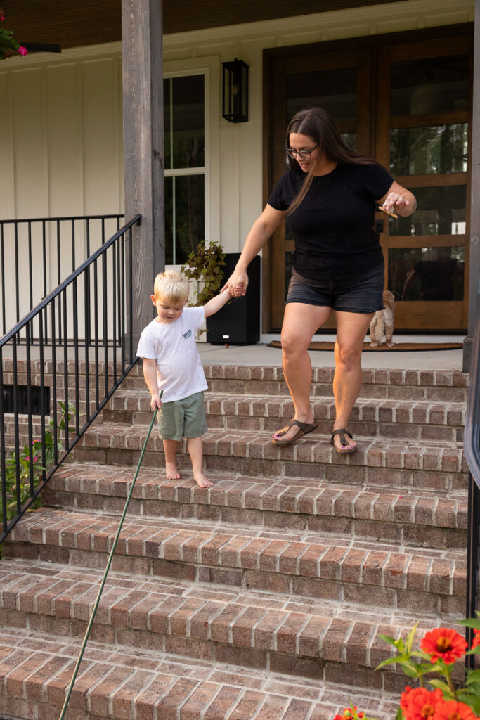 Mom and young son walking down the front steps of their home together.
