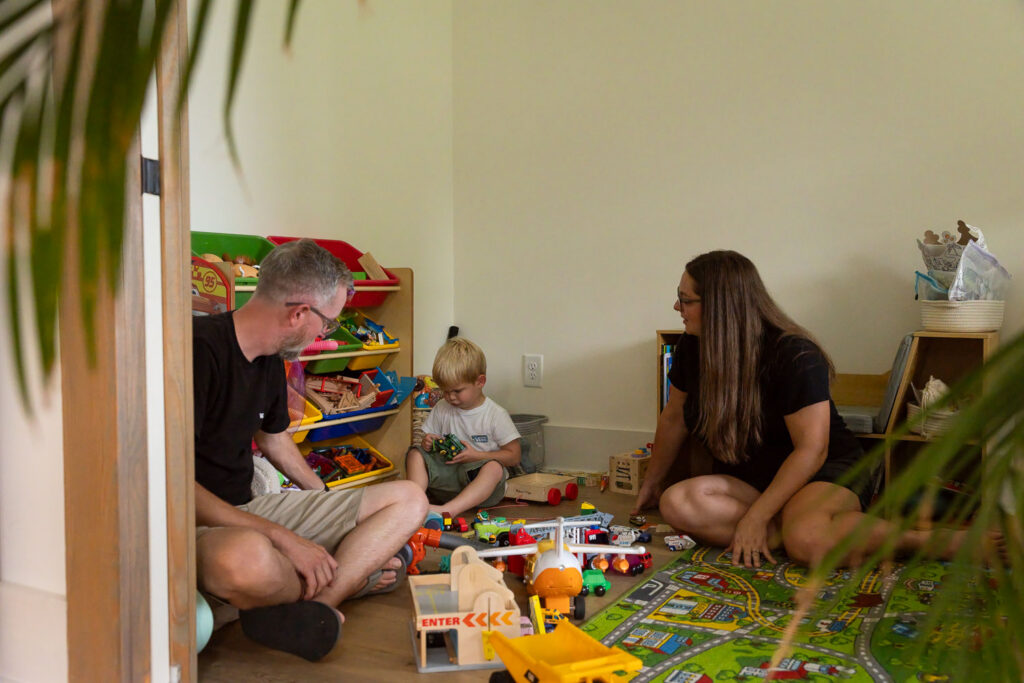 Family spending time together on the floor surrounded by colorful toys in their home.