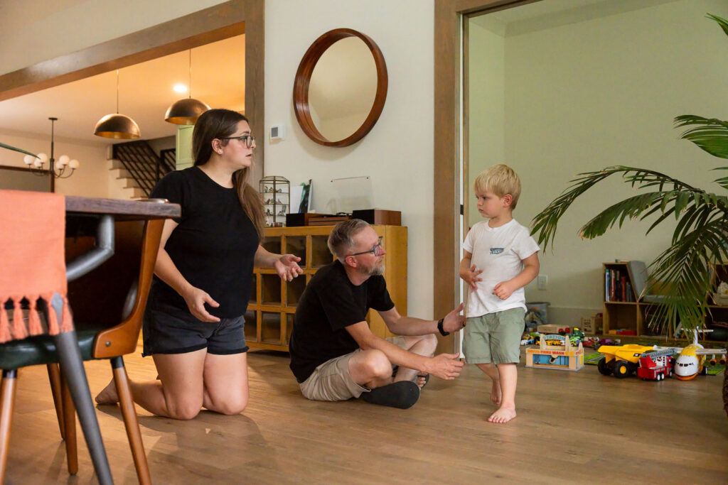 Toddler walks toward parents seated on the floor after a minor injury